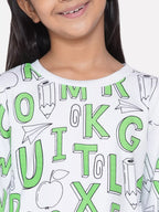 Child wearing a white shirt with green letters and symbols