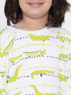 Child wearing a white shirt with green dinosaur prints on a plain background
