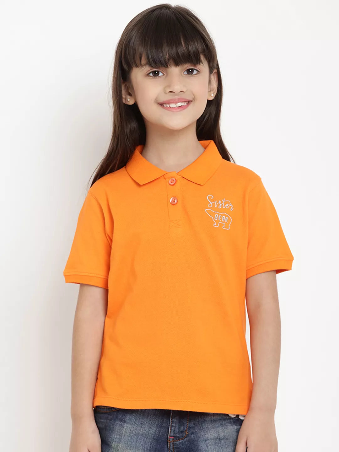 Young girl wearing an orange polo shirt with a logo on a white background