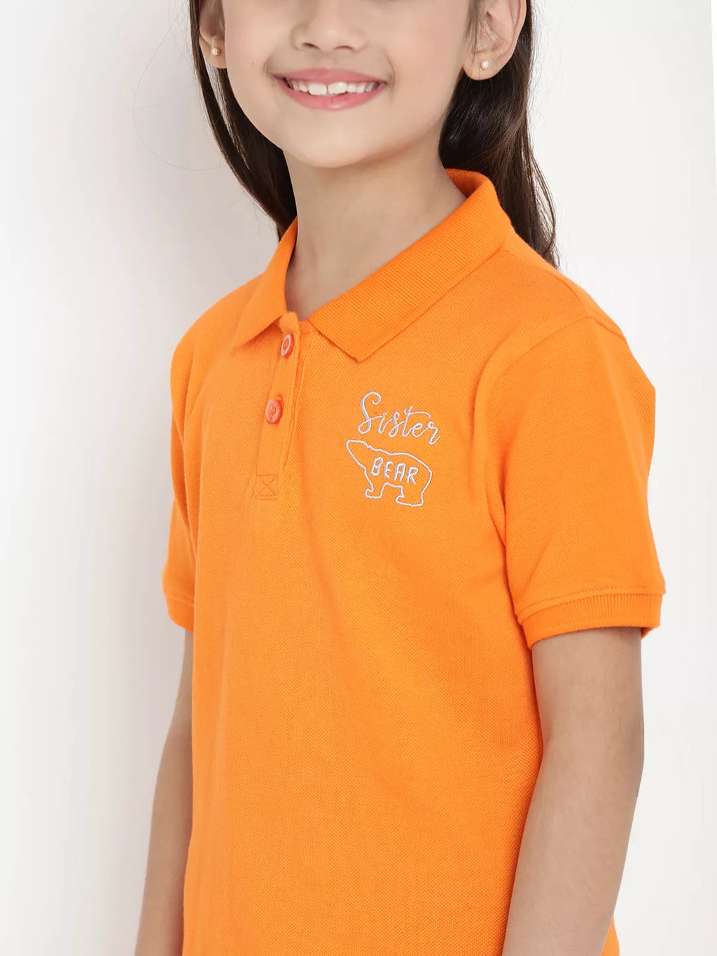 Child wearing an orange polo shirt with a logo on a white background