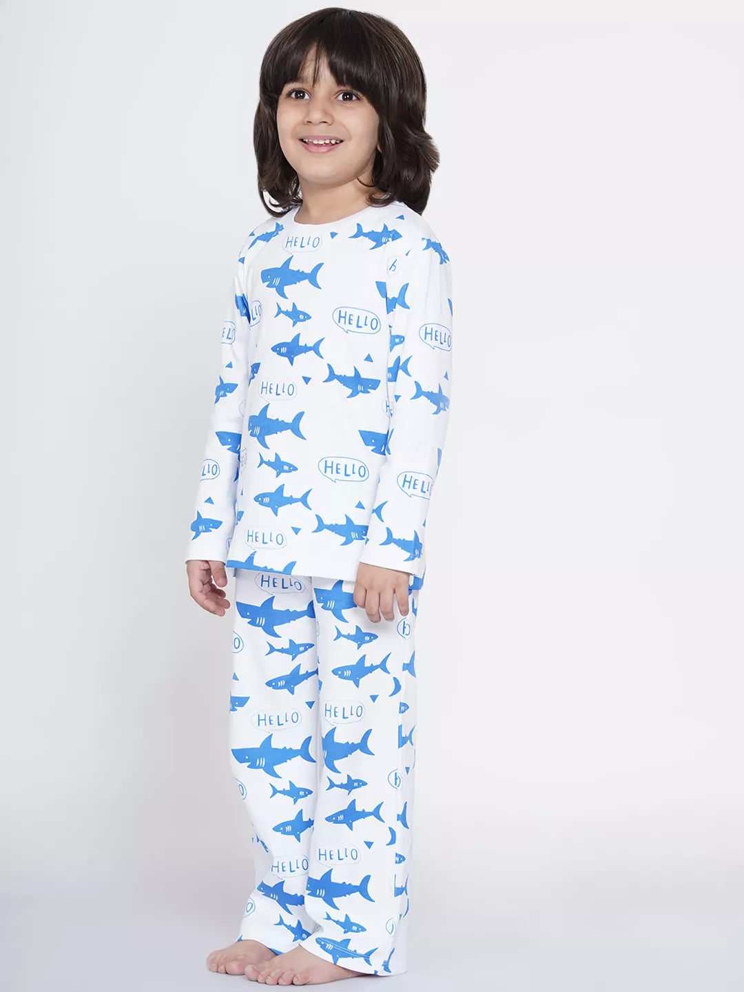 Child wearing a pajama set with shark pattern on a white background