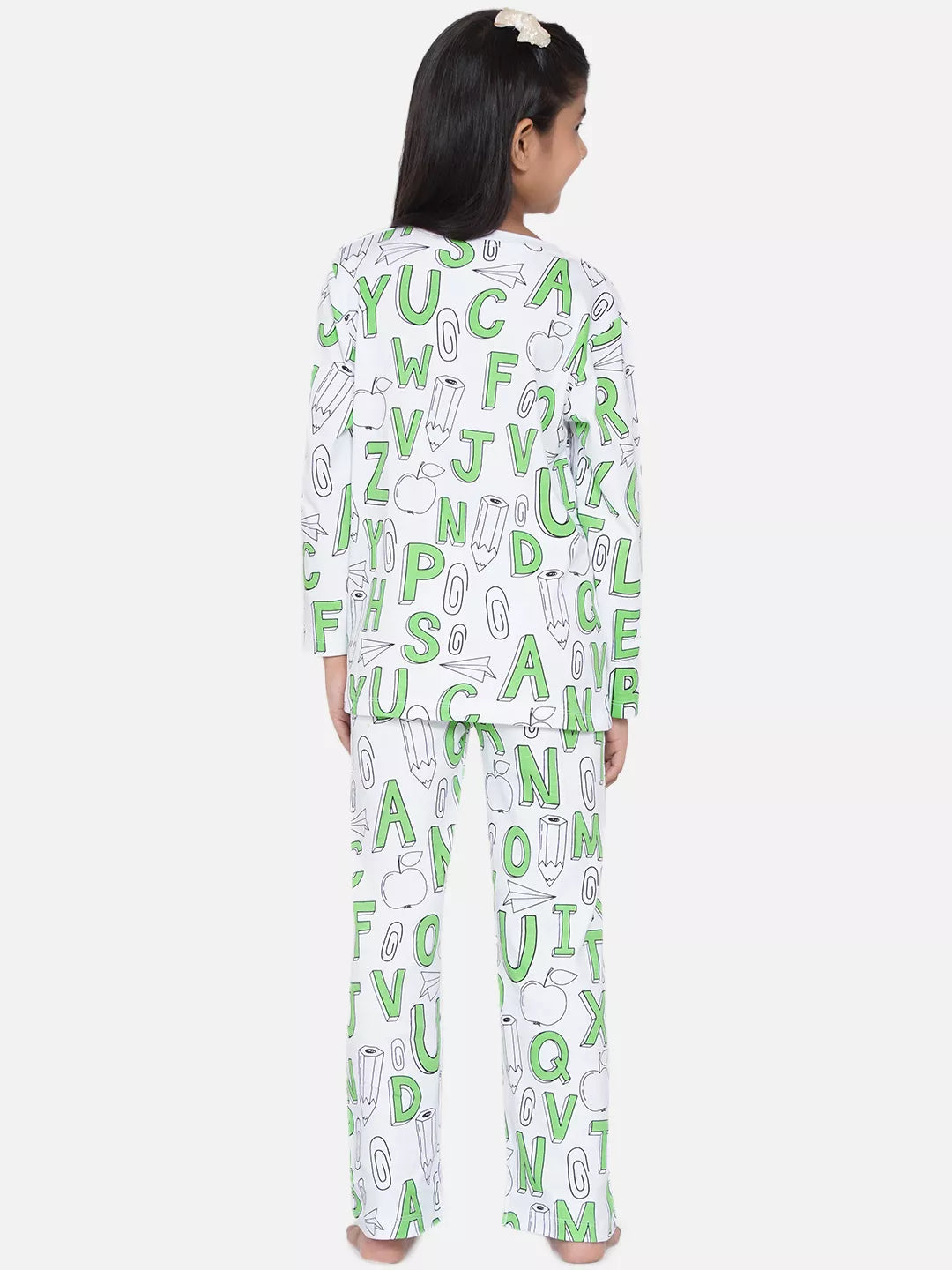 Child wearing a green and white pajama set with alphabet pattern on a white background