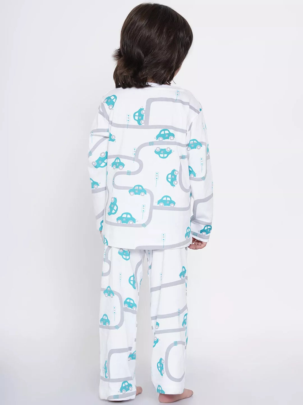 Child wearing a white pajama set with blue car patterns on a white background