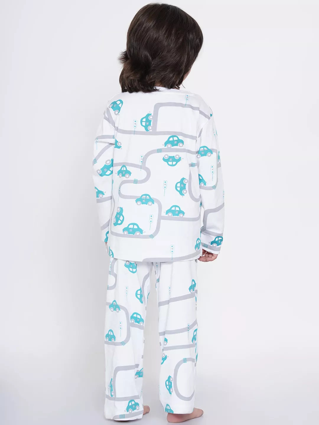 Child wearing a white pajama set with blue car patterns on a white background