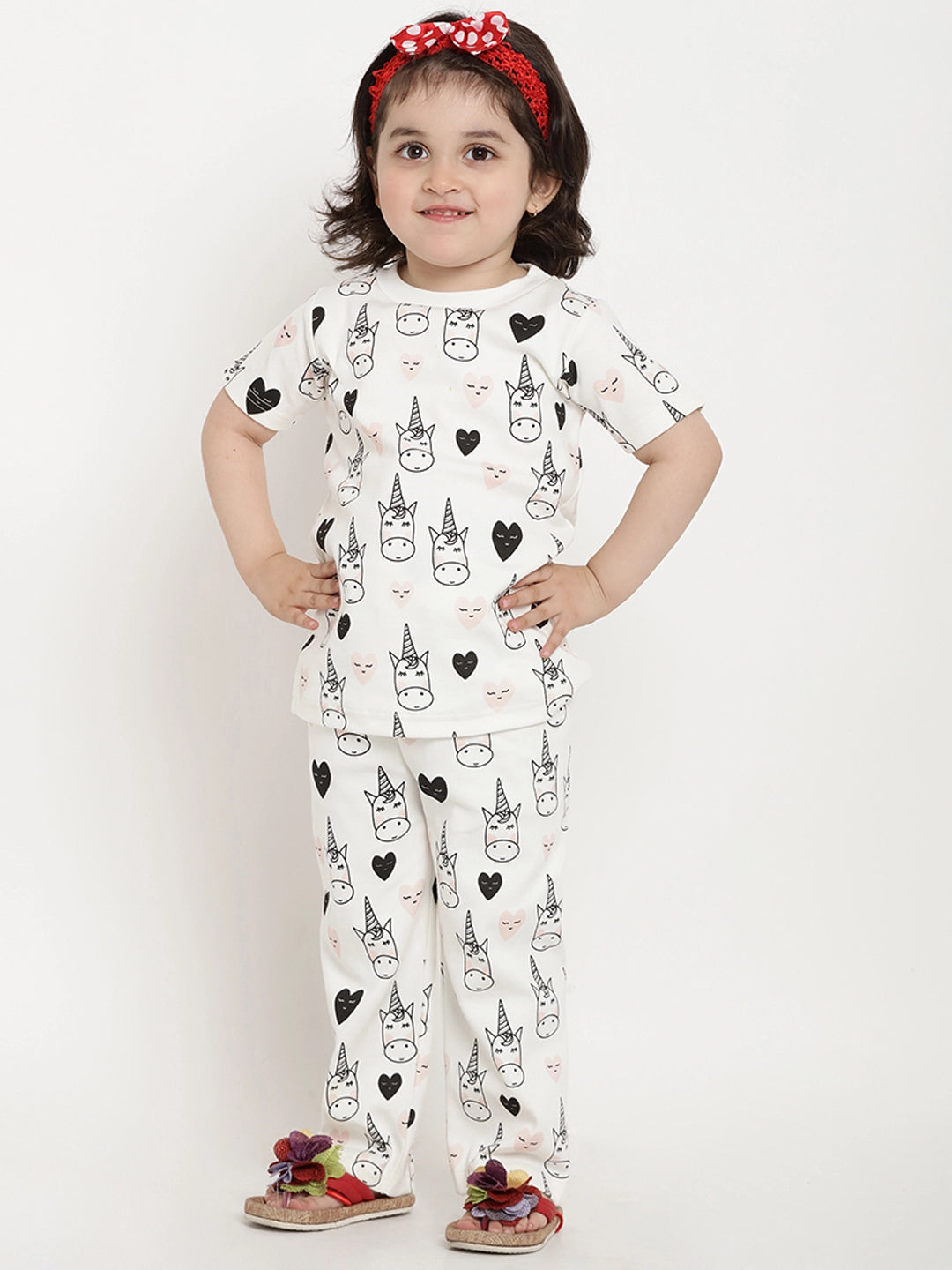 Child wearing a pajama set with unicorn and heart patterns on a white background