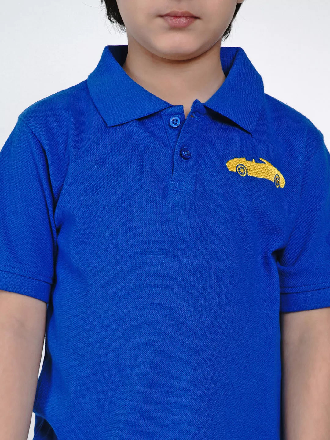 Child wearing a blue polo shirt with a yellow car emblem on a white background