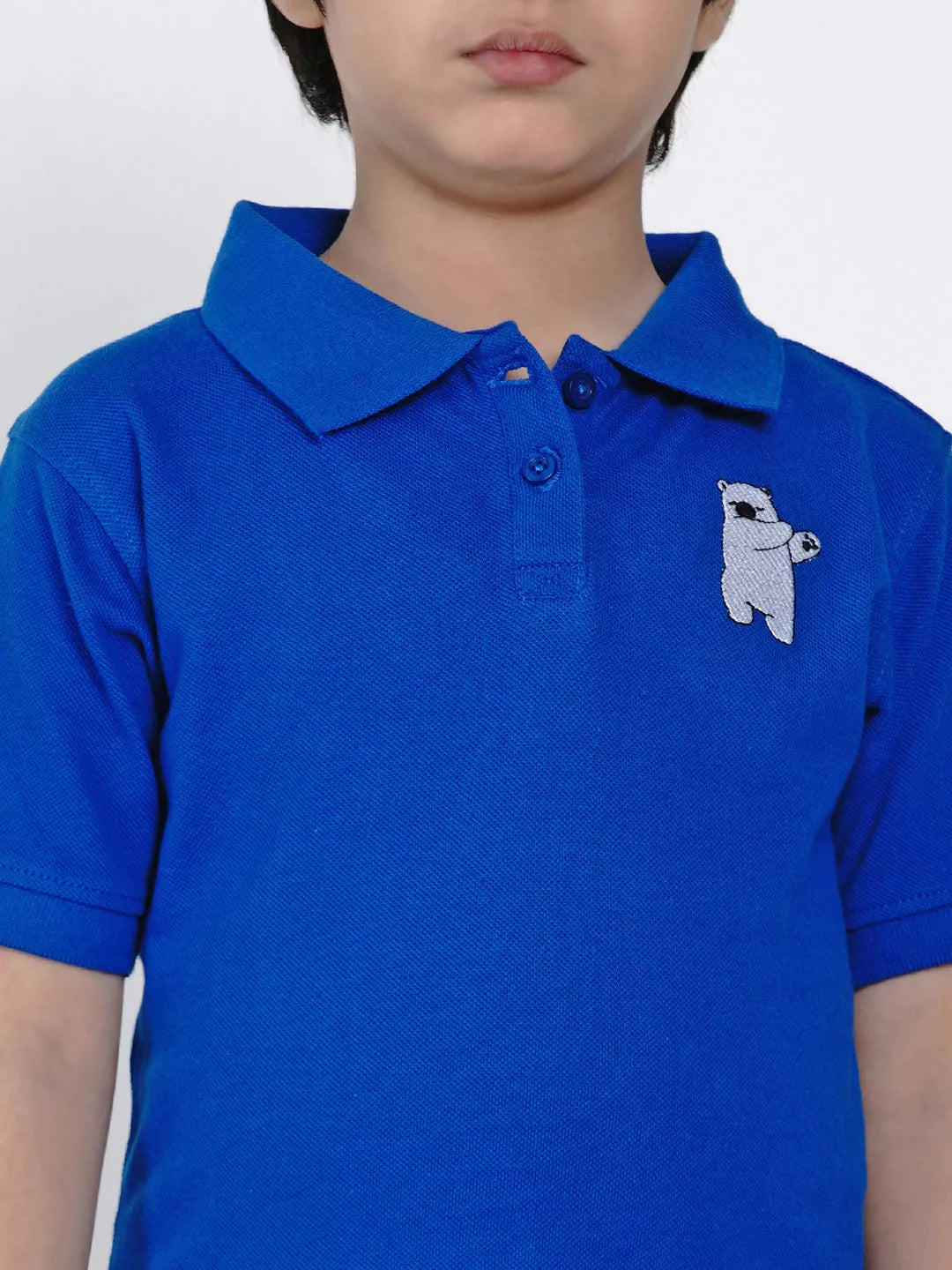 Child wearing a blue polo shirt with a white bear design on a plain background