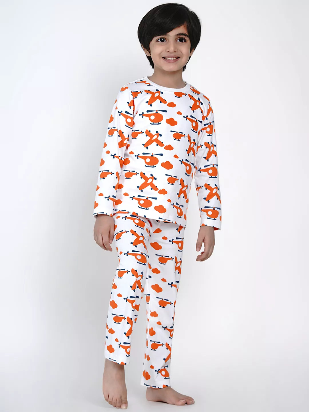 Child wearing a white pajama set with orange helicopter pattern on a white background