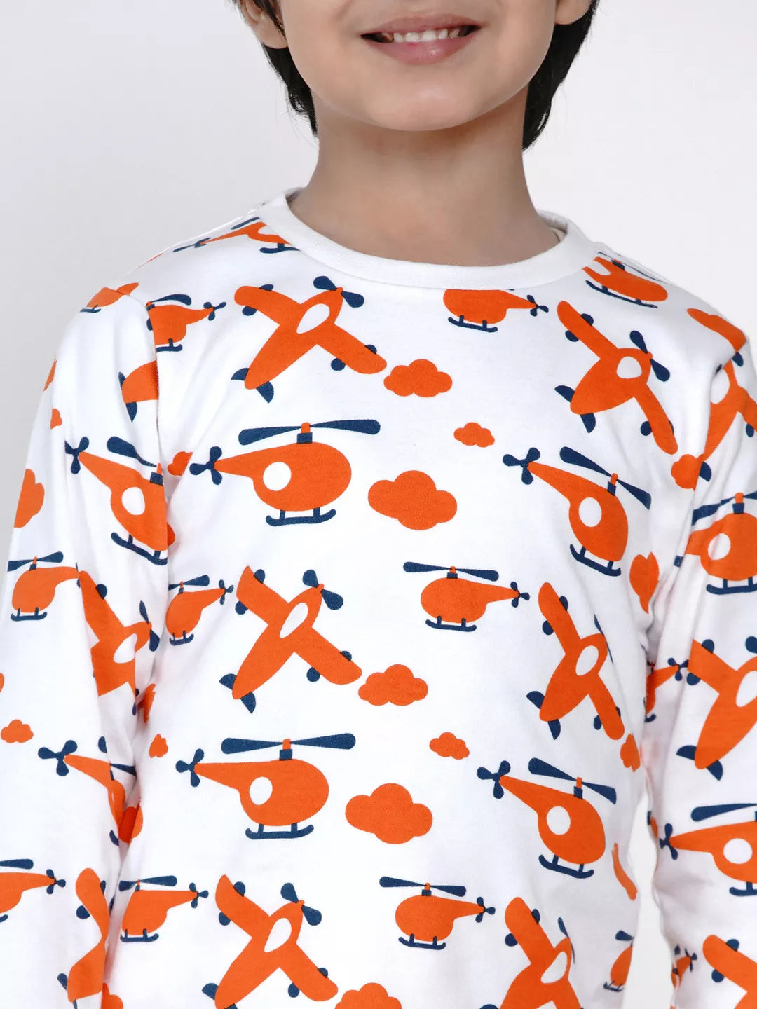 Child wearing a long-sleeve shirt with orange helicopter pattern on a white background