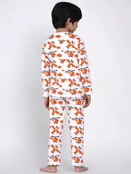 Child wearing a white pajama set with orange airplane pattern on a plain background