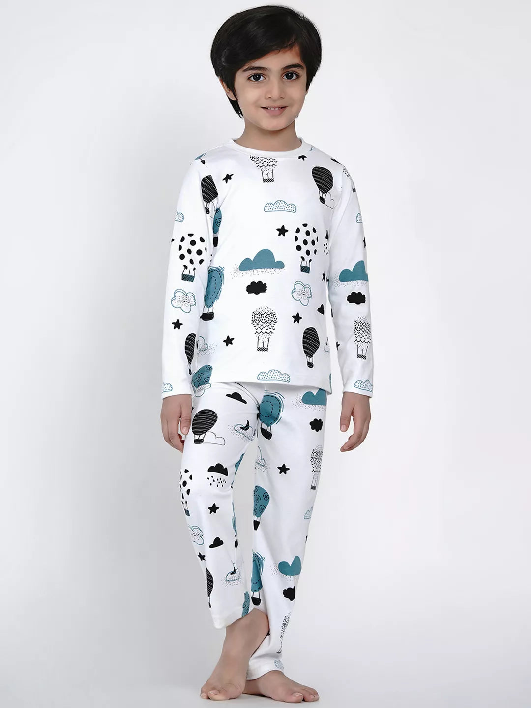 Child wearing a white pajama set with cloud and animal patterns on a plain background