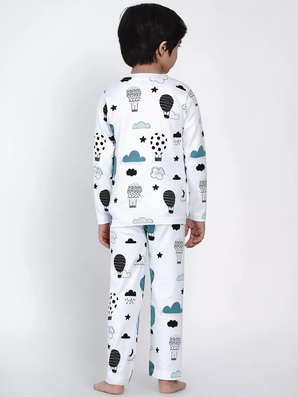 Child wearing a white pajama set with black and blue cloud, star, and hot air balloon patterns on a white background.