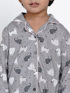 Child wearing a gray pajama shirt with animal pattern on a white background