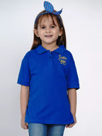 Young girl wearing a blue polo shirt with 'Sister' printed on it, against a white background