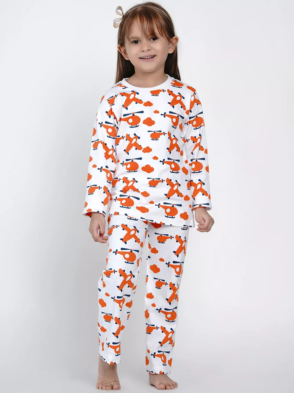 Child wearing a white long-sleeve shirt and pants with orange airplane pattern on a white background