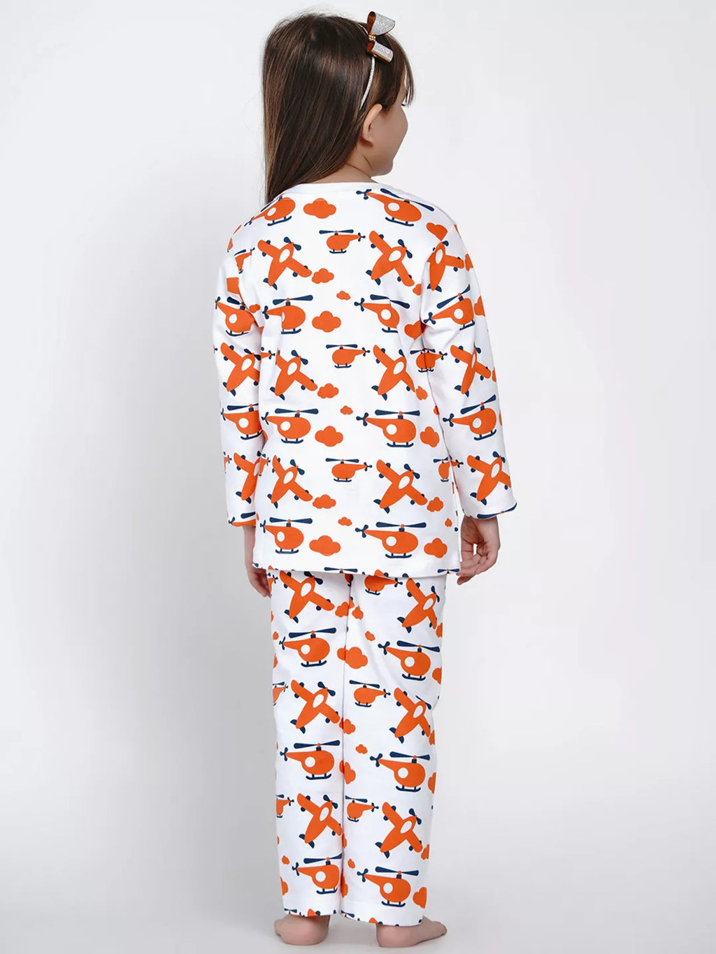 Child wearing a pajama set with orange airplane pattern on a white background
