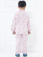 Child wearing a pink and white pajama set with a pattern on a white background