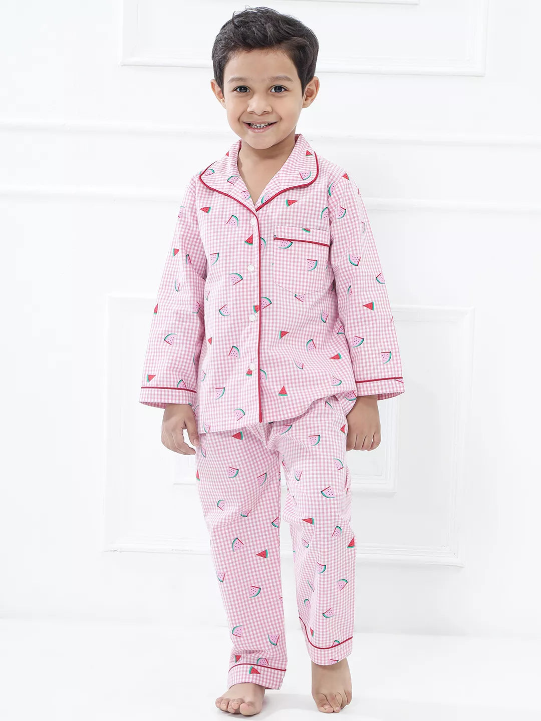 Child wearing pink checkered pajamas with red trim on a white background
