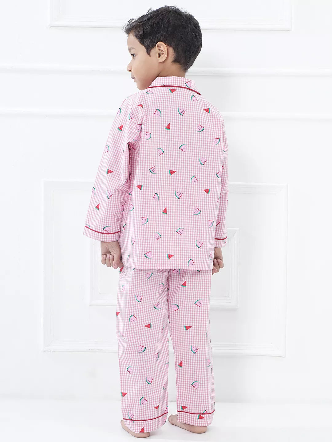 Child wearing pink checkered pajamas with heart patterns on a white background
