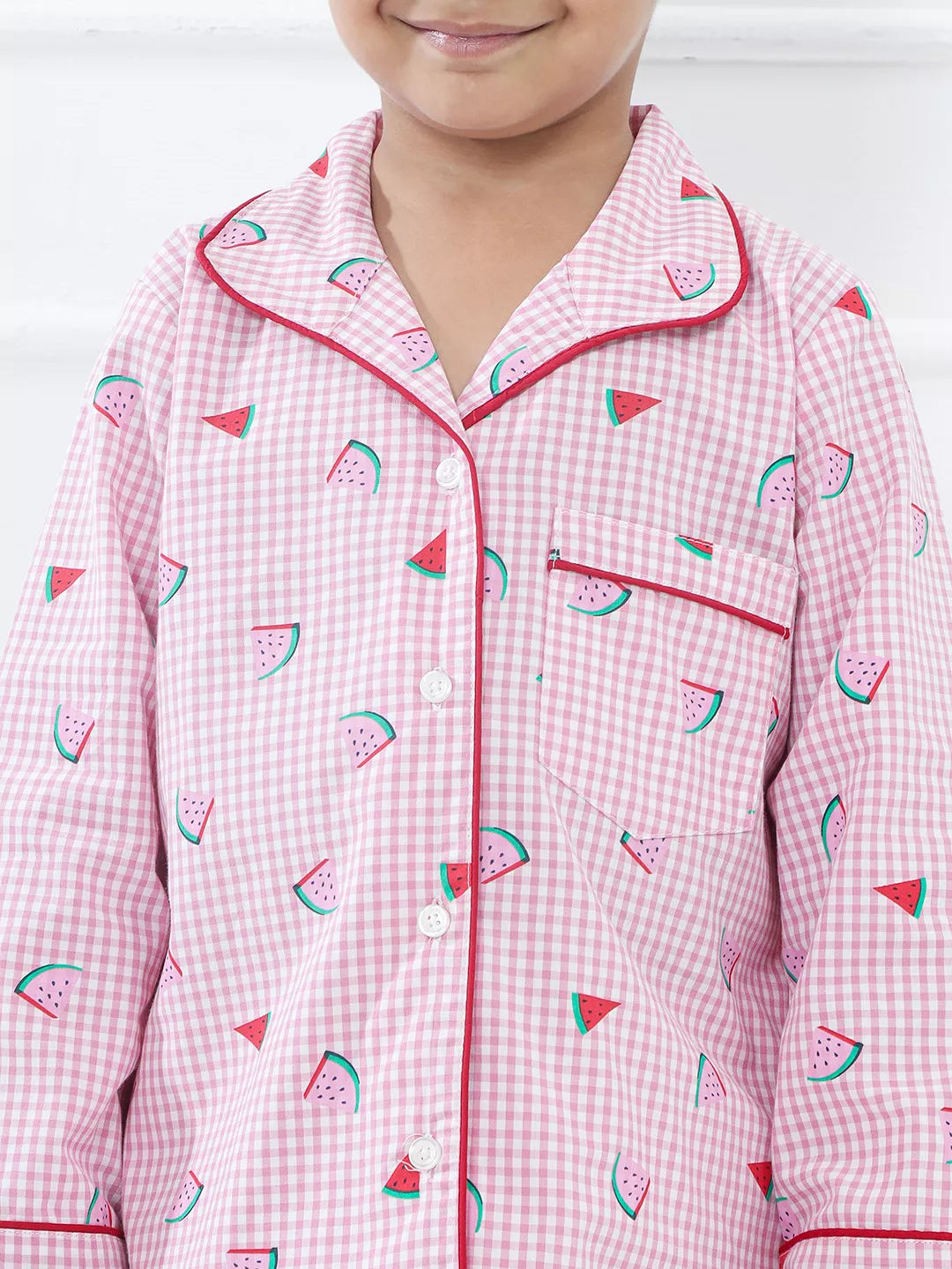 Child wearing a pink gingham pajama set with watermelon pattern