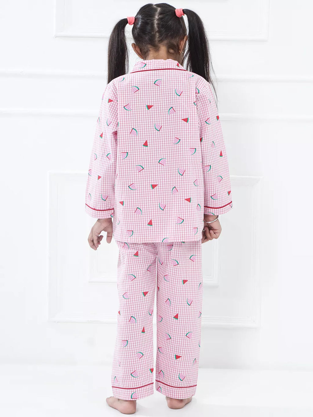 Child wearing pink checkered pajamas with red trim on a white background