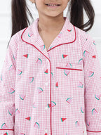 Child wearing pink checkered pajamas with watermelon pattern on a white background