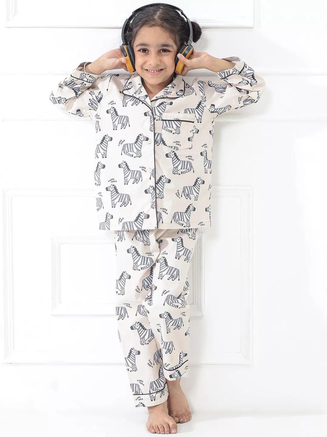 Child wearing zebra-patterned pajamas with headphones on a white background