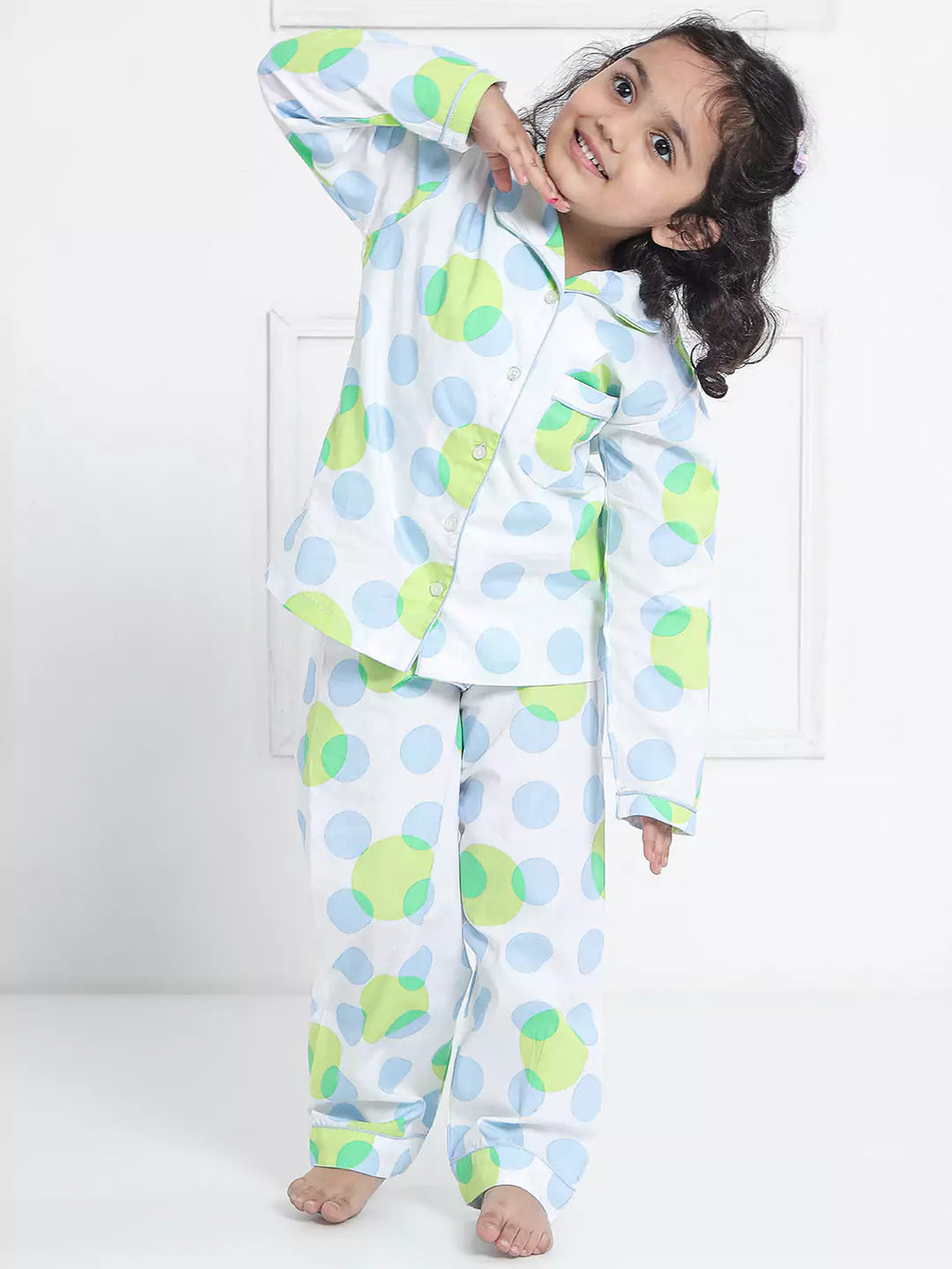 Child wearing a colorful polka dot pajama set on a white background