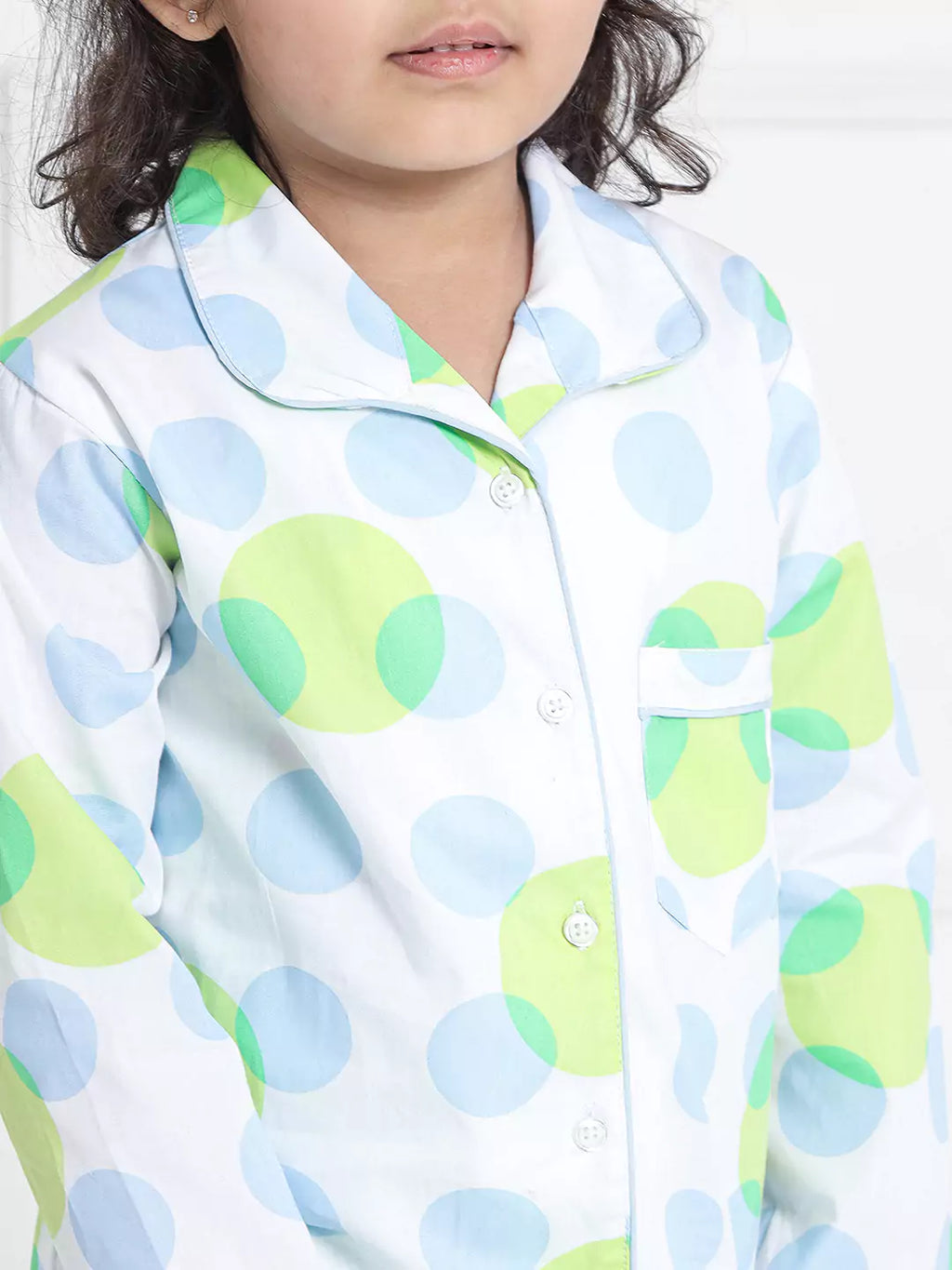 Child wearing a shirt with green and blue pattern on a white background