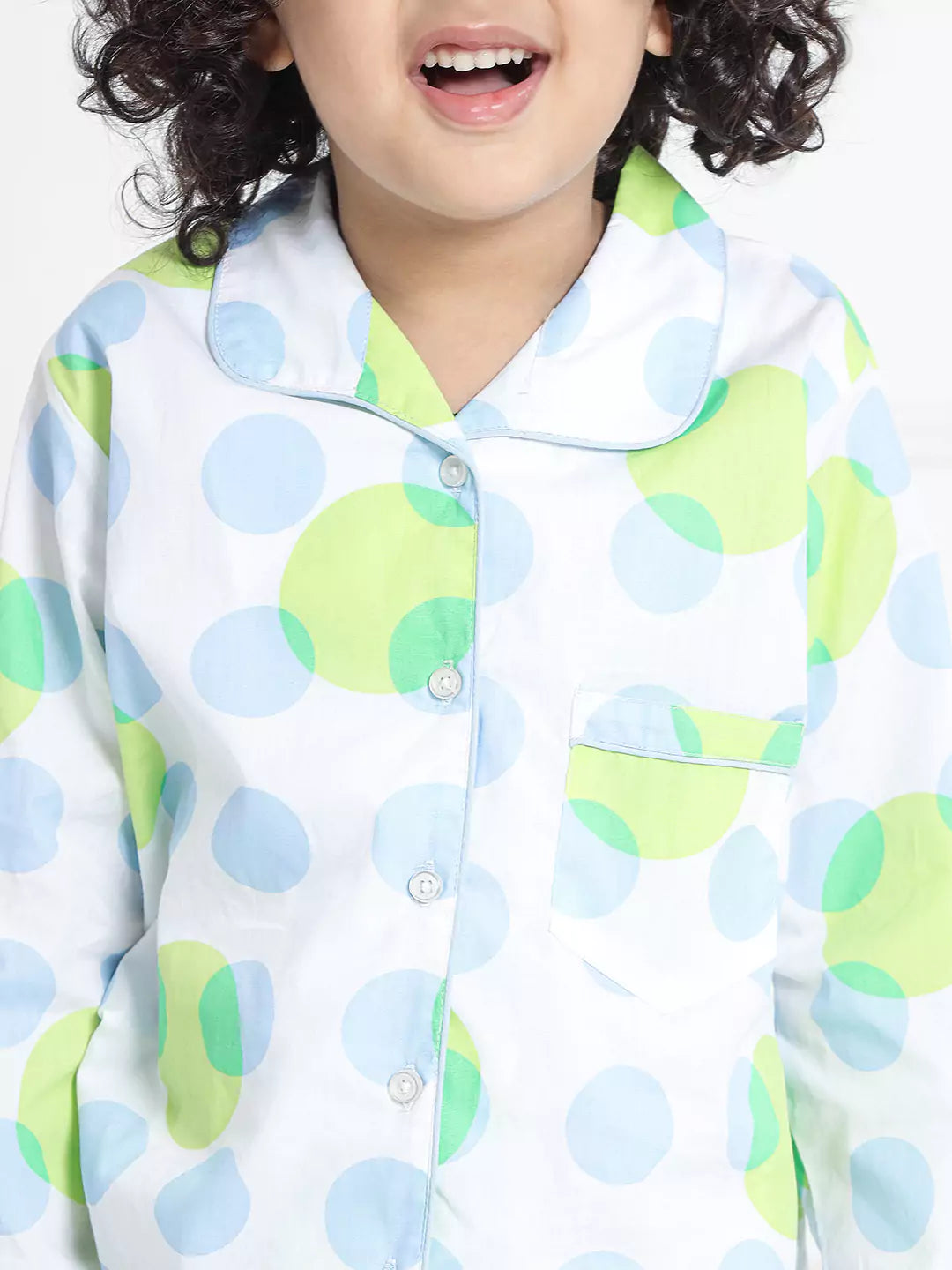 Boy wearing a colorful polka dot shirt with a white background