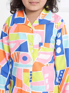 Child wearing a colorful geometric patterned shirt on a white background