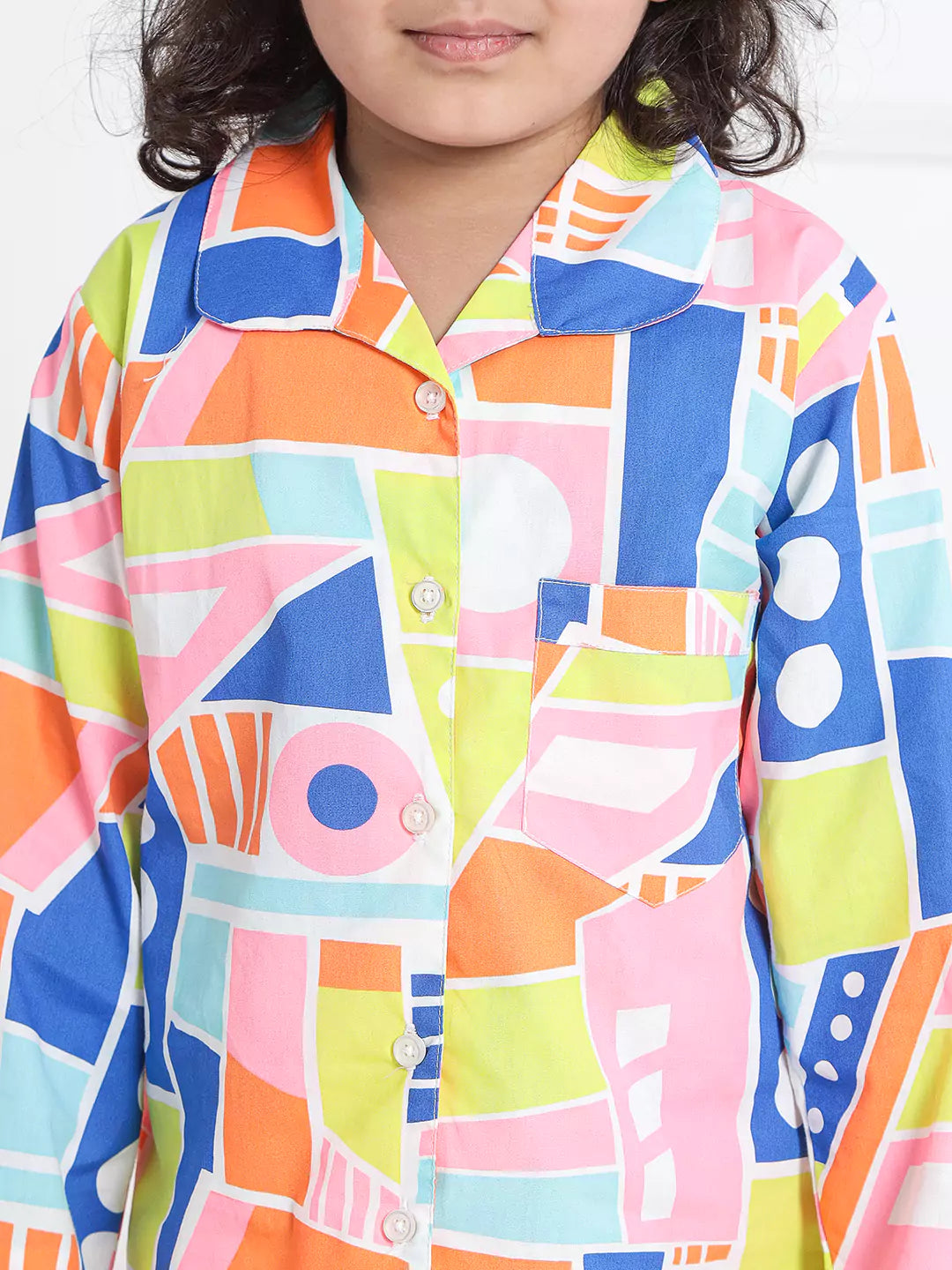 Child wearing a colorful geometric patterned shirt on a white background