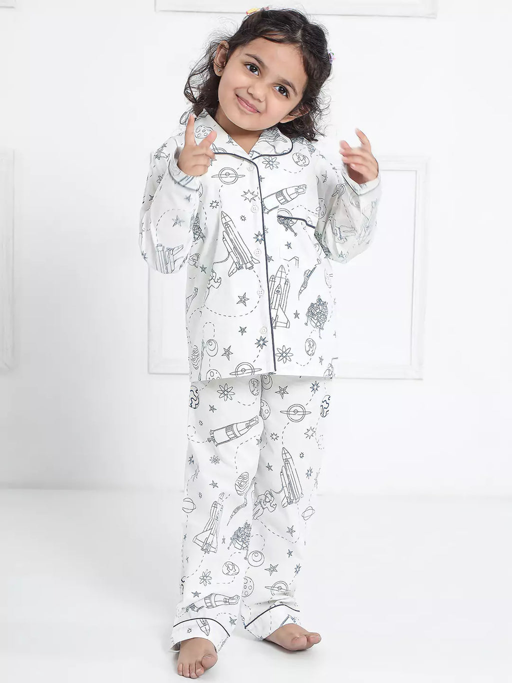 Child wearing a white pajama set with black patterns on a white background