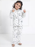Child wearing a white pajama set with black patterns on a white background