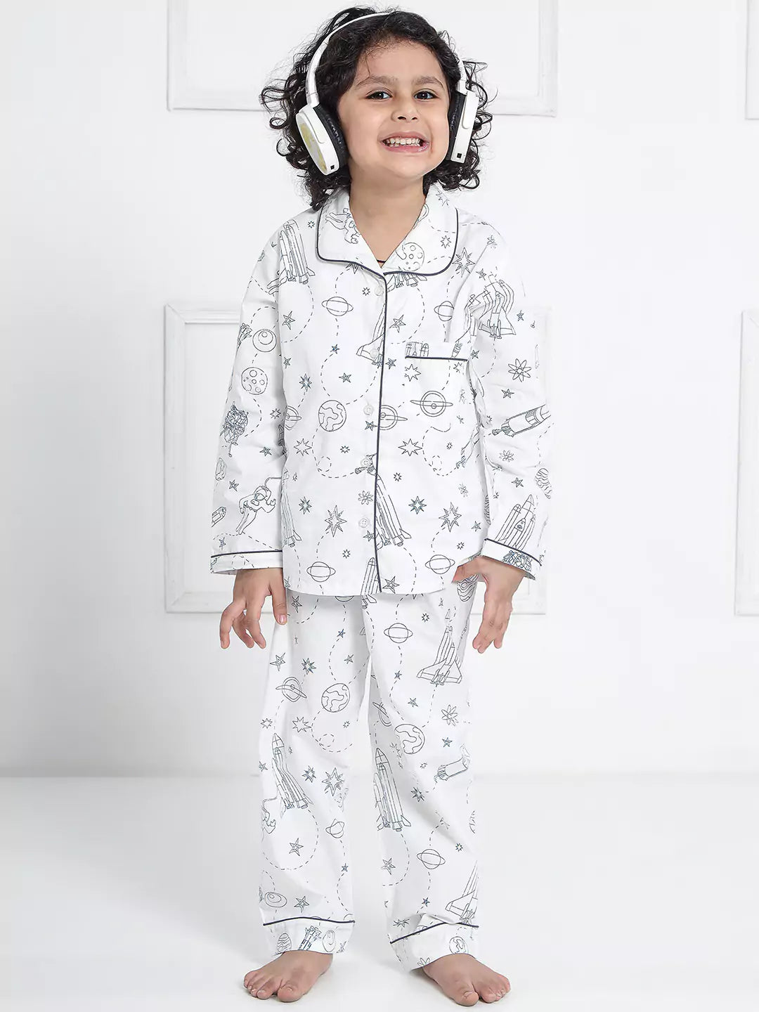 Child wearing a white pajama set with space-themed design on a white background